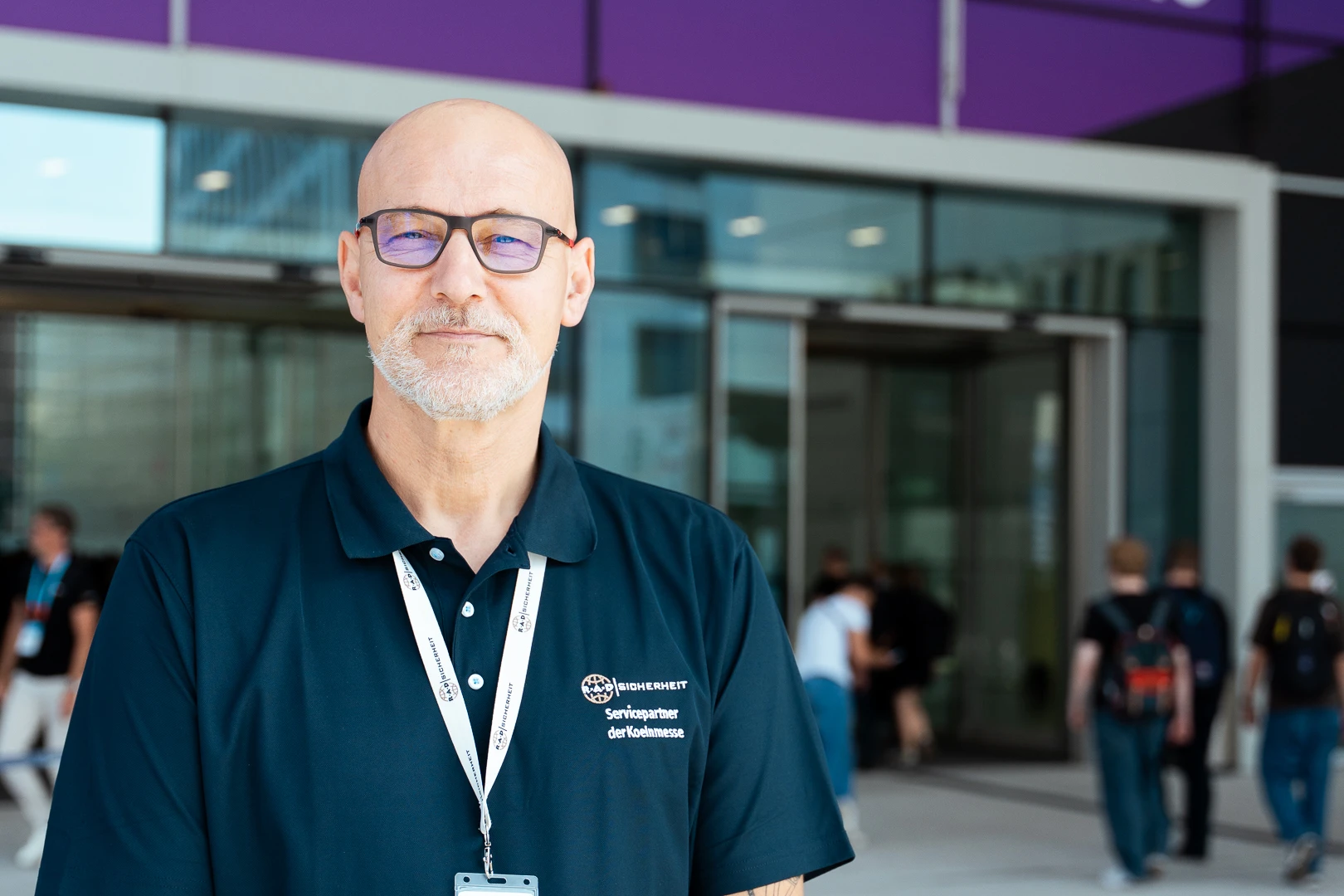 objektschutz-messe Sicherheitsmitarbeiter in Dienstkleidung vor einem Eingang eines großen Gebäudes